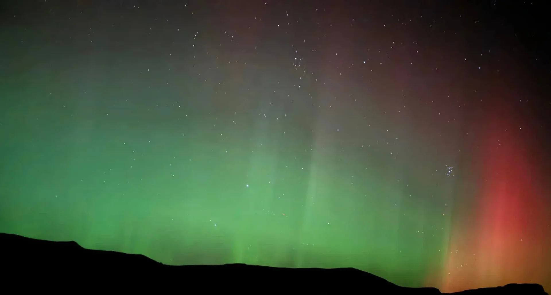 Green and red aurora above the cliffs